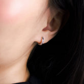 Fine jewellery, silver jewellery, hypoallergenic, tarnish-free, close-up right view of a silver hoop earrings embedded with crystals worn on a person's ear